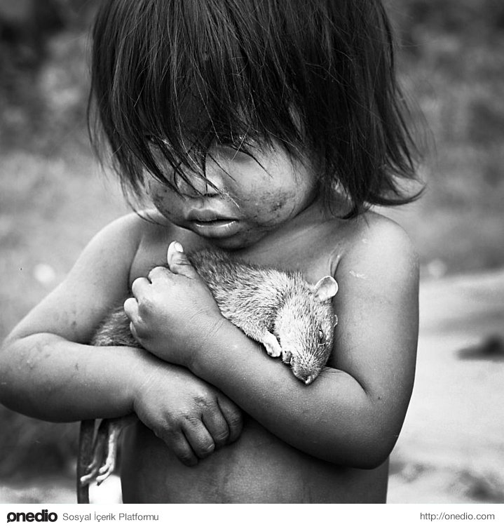 Küçük Guarani kız, ölü bir sıçanı elinde tutarken.